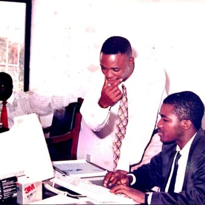 Mr. Niyi Yusuf sitting at his computer with another colleague